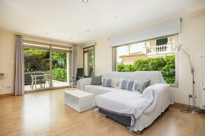 A modern living room with a sofa, a coffee table, and a large window with a view of greenery.