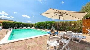 A swimming pool with lounge chairs and an umbrella, surrounded by greenery. - Holiday Home 'Calypso Sea View Holiday House 2' with Sea View, Wi-Fi and Air Conditioning (Badesi)