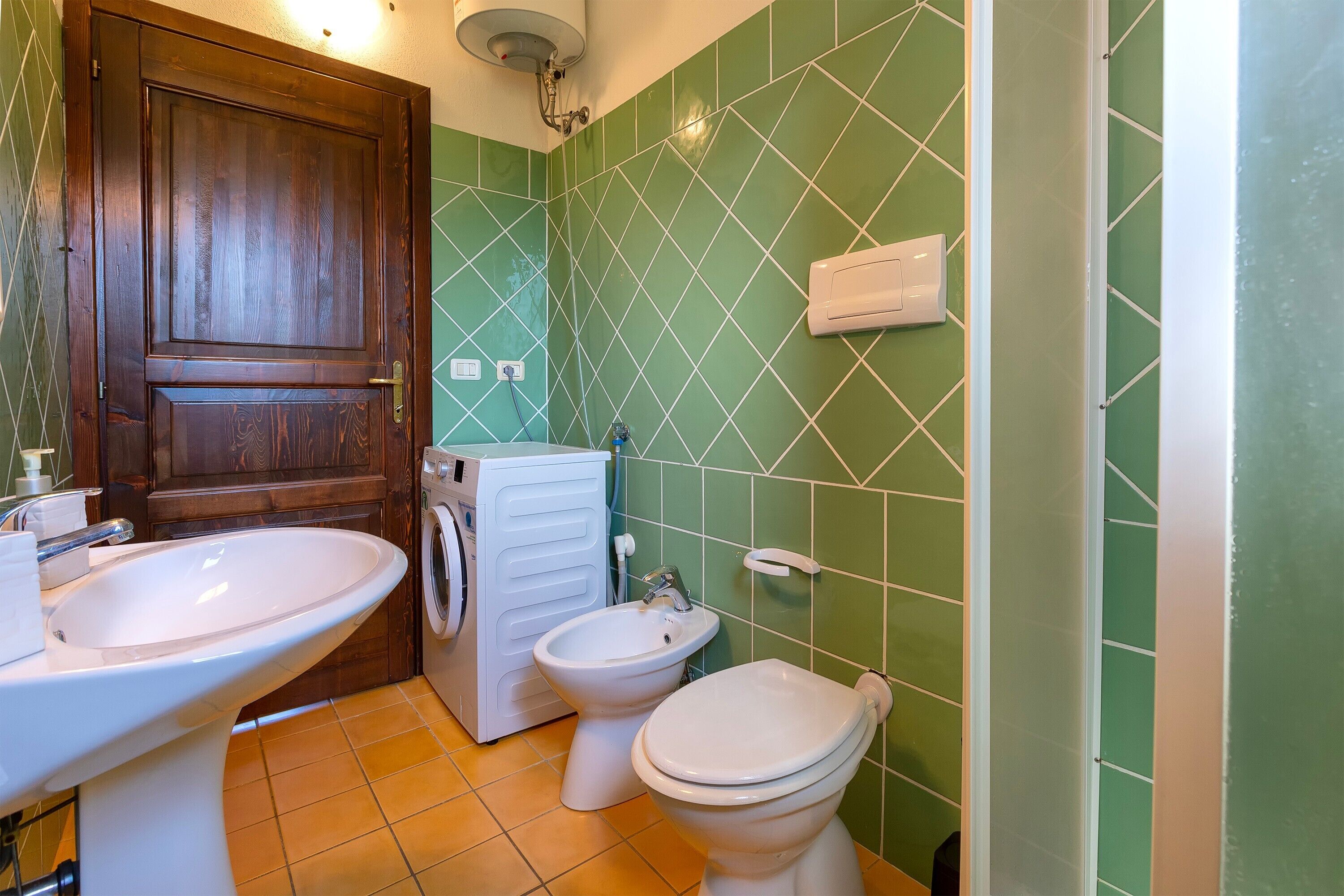 Un baño con lavamanos, bidé, inodoro y lavadora.