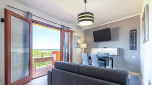 A modern living room with a sofa, a TV, and a balcony with a view.
