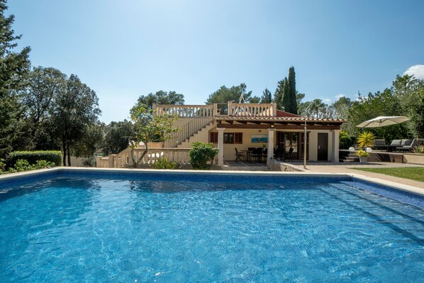 Una piscina con una casa al fondo.