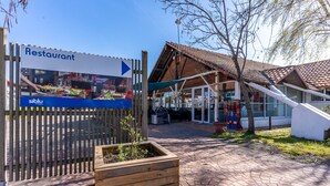 A restaurant sign, wooden fence, and a building with a tiled roof.