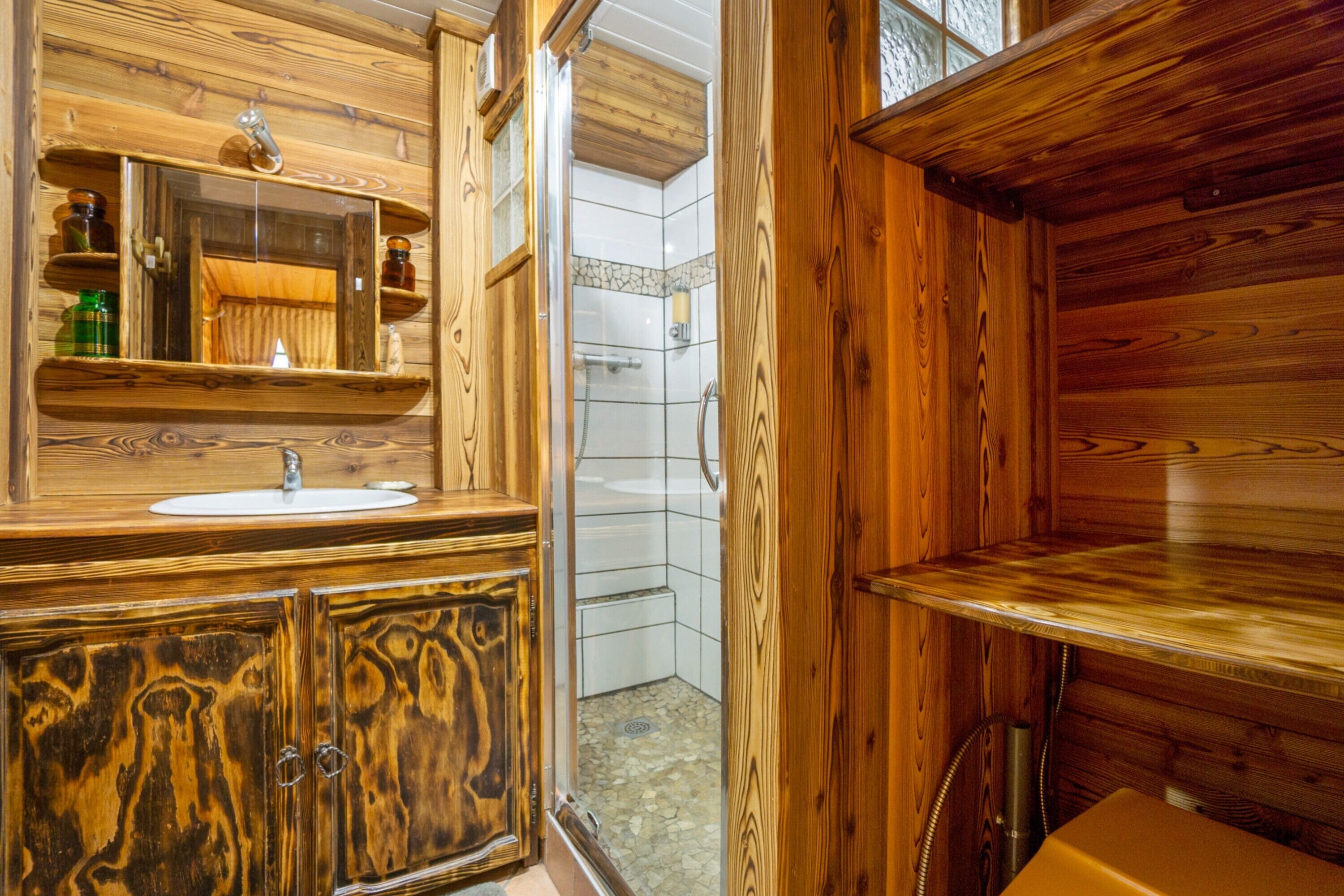Une salle de bain en bois avec un lavabo, un miroir et une douche.