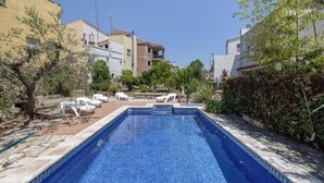 Una piscina con sillas de descanso, rodeada de edificios y vegetación.