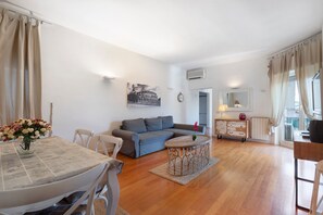 A living room with a sofa, a dining table with chairs, a small round table, and a decorative vase. - Holiday Home 'Romantic Apartment Metro Flaminio' with Wi-Fi and Air Conditioning (Roma)