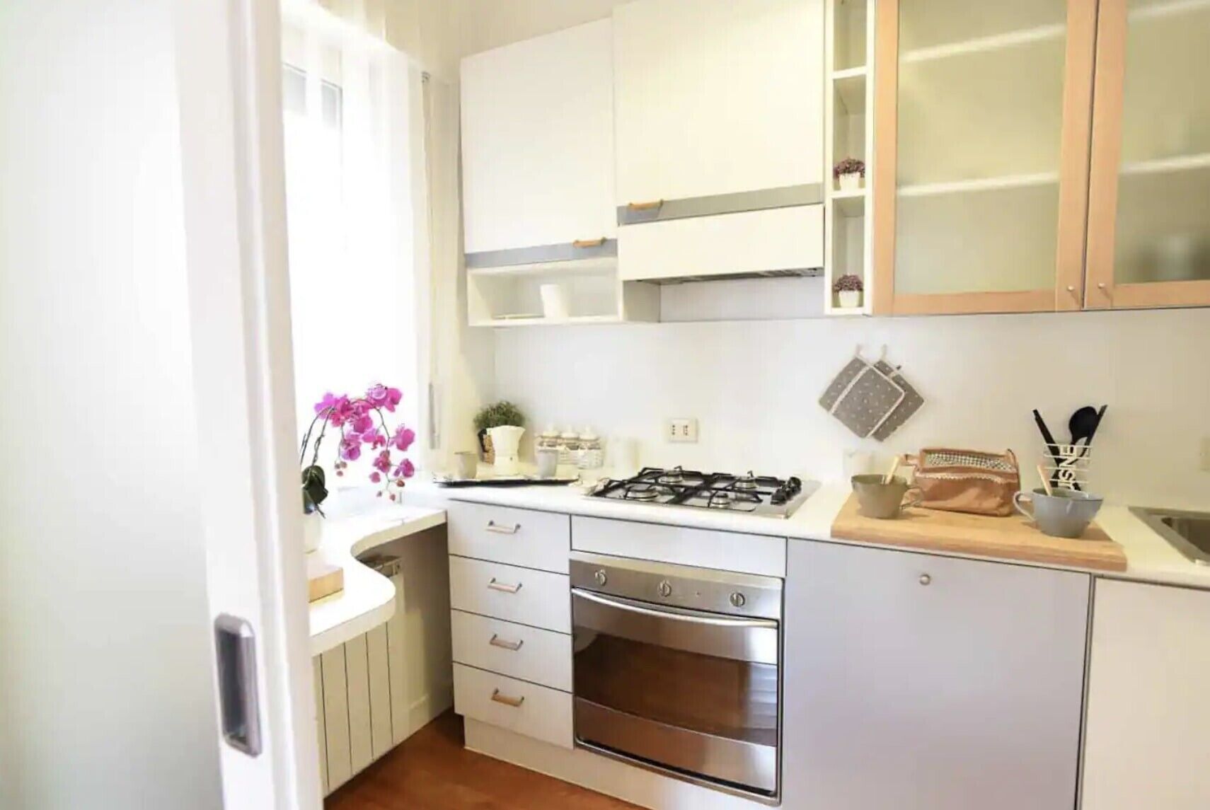 A compact kitchen with white cabinets, a gas stove, an oven, and a small countertop with kitchen utensils.