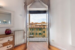 Ein schmaler Gang führt zu einem Balkon mit Blick auf Gebäude.