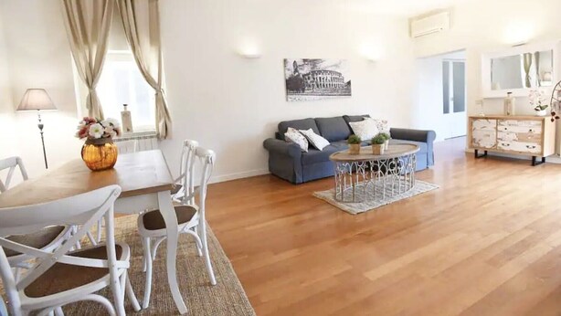 Una sala de estar con una mesa de comedor, sillas, un sofá, una mesa de centro y un mueble de almacenamiento.