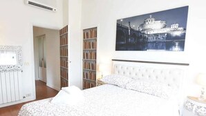 Un dormitorio con cama, una estantería, un radiador y un cuadro en la pared.