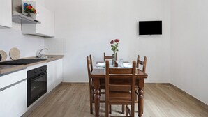 Una cocina moderna con una mesa de comedor, sillas, un televisor y un horno empotrado.
