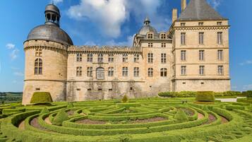 Ein historisches Gebäude mit einem großen zentralen Turm, einer Kuppel und einem formalen Garten mit Labyrinth.