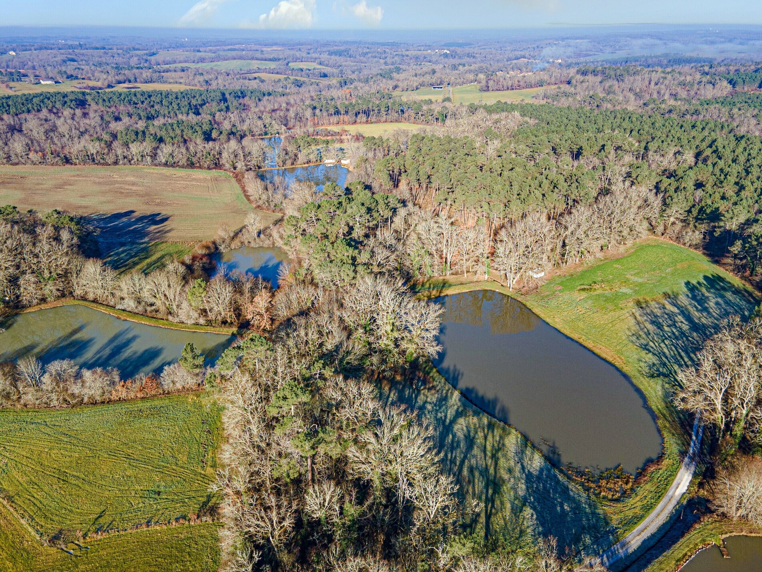 Vue aérienne d’un paysage rural avec des champs, des étangs et de vastes forêts.