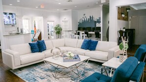 A modern hotel lobby with a white sectional sofa, blue chairs, and a coffee table.