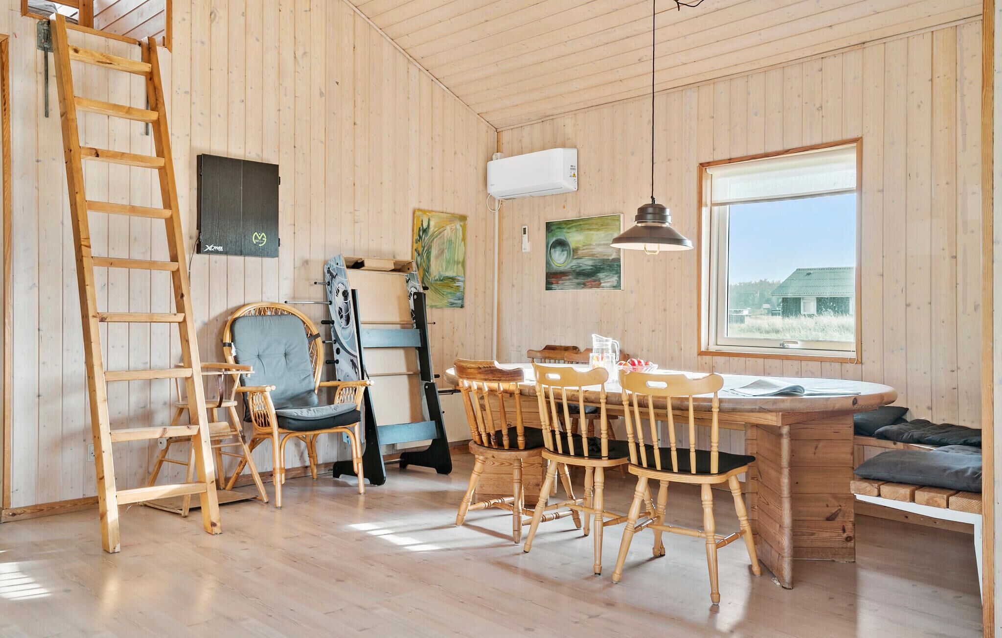 Un intérieur en bois comprenant un coin repas, une échelle et un lit superposé.
