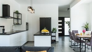 Une cuisine moderne avec un îlot central, un coin repas avec une table et des chaises, et un canapé agrémenté d’un coussin.