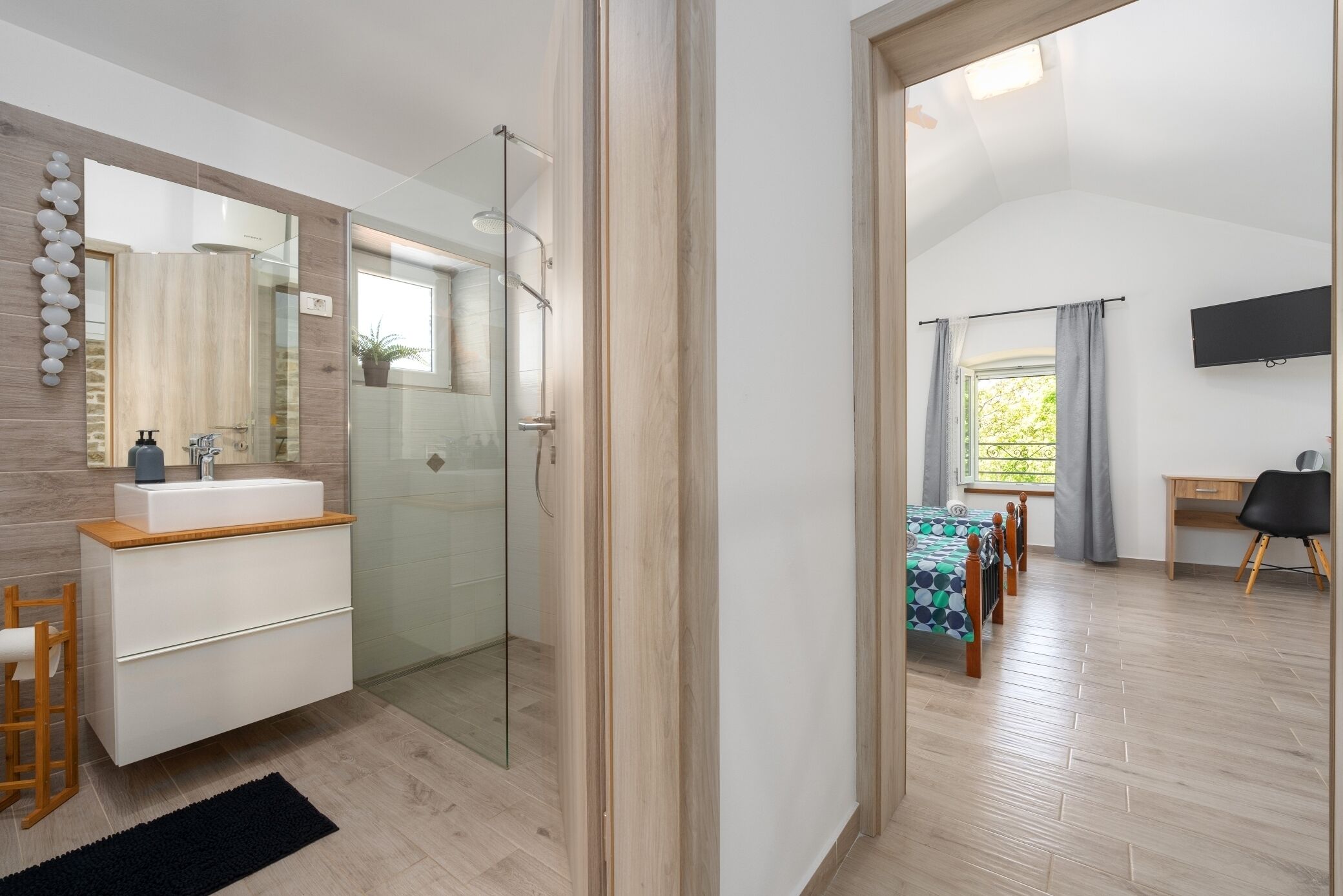 Une salle de bain moderne avec une douche à parois de verre, un meuble-lavabo en bois et un grand miroir.