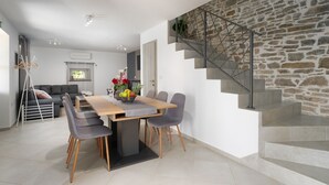 Un salon moderne avec un coin repas, un escalier aux murs en pierre et un design minimaliste.