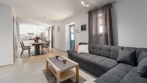 Un salon moderne avec un canapé gris, une table basse en bois et un coin repas comprenant des chaises et une table.