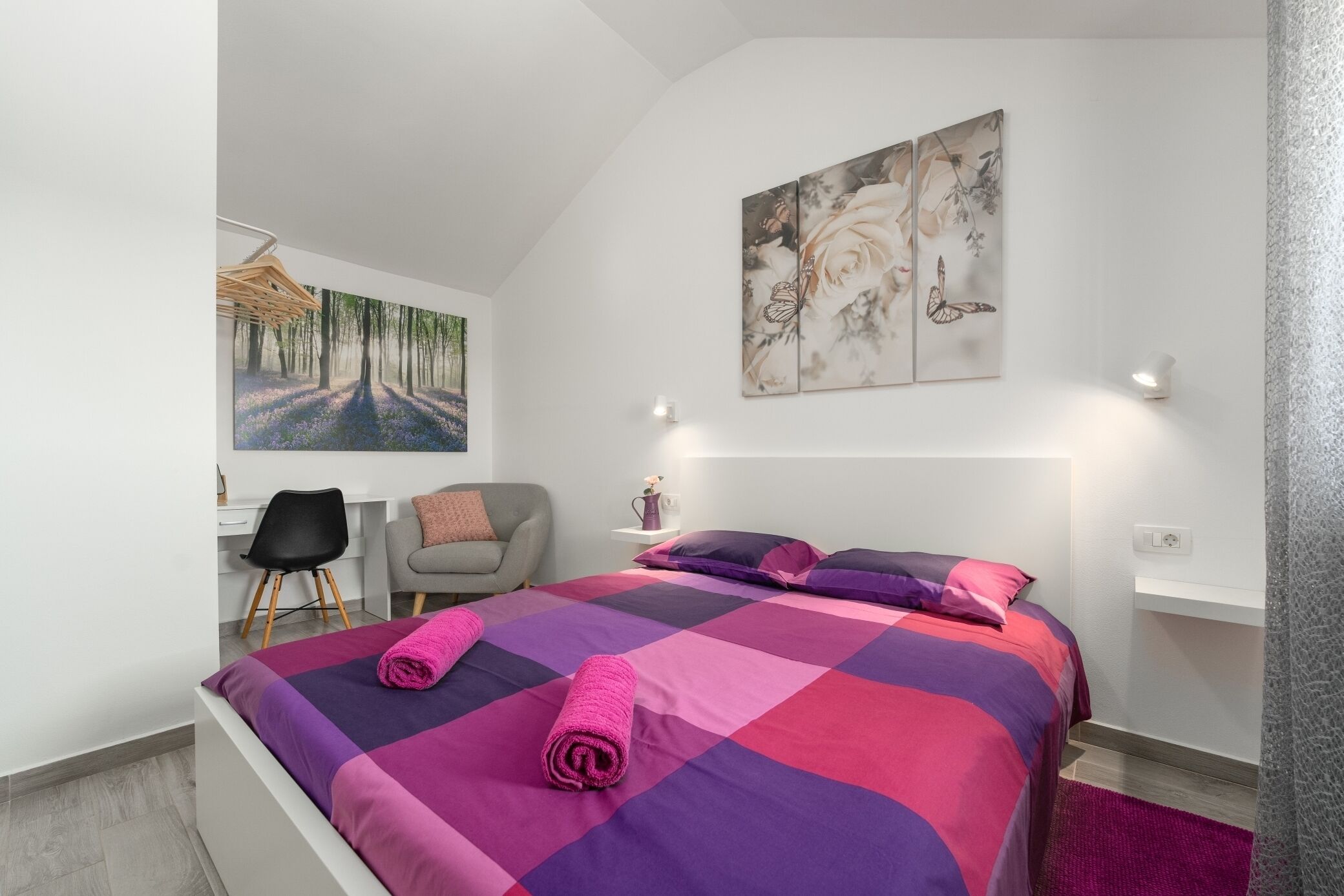 A modern bedroom with a large bed, a desk, and a chair.