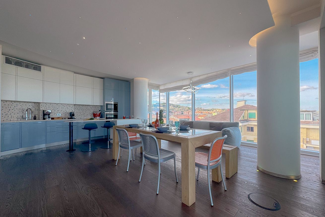 Eine moderne Küche mit Essbereich, großen Fenstern und Blick auf die Stadt.