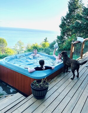 A hot tub on a wooden deck with a view of the sea. - Paradise Suites (Homer)