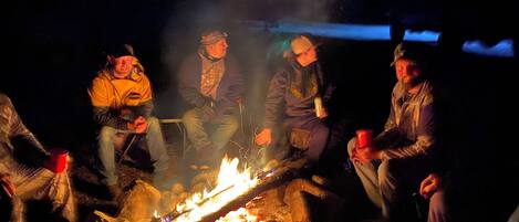 A group of people sitting around a campfire at night.