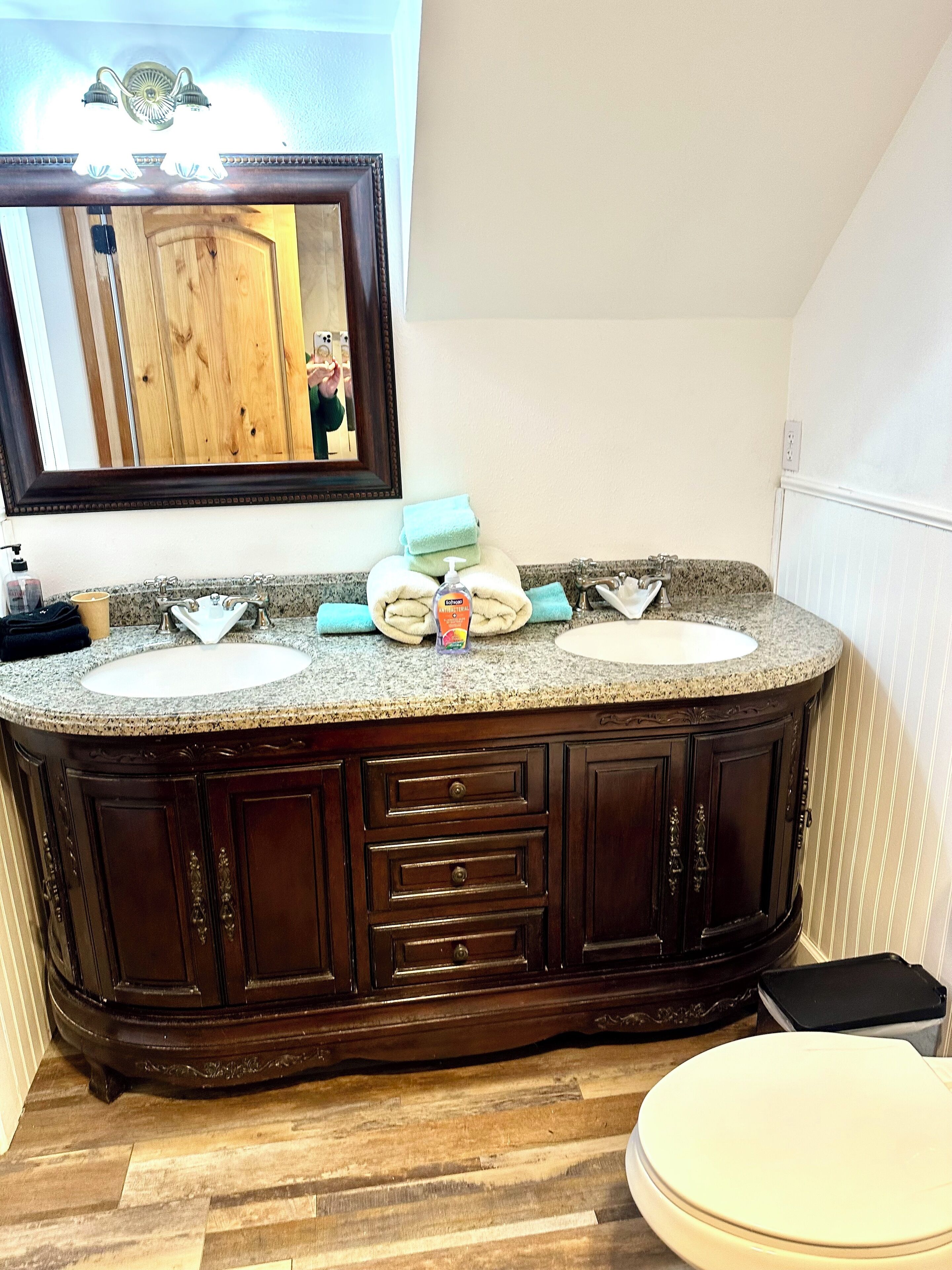 A bathroom with a double sink vanity, a mirror, and a toilet.