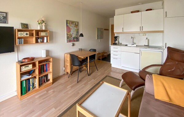 Ein moderner Wohnbereich mit einem Holzesstisch, einer Couch, einer Küchenzeile und einem Bücherregal.