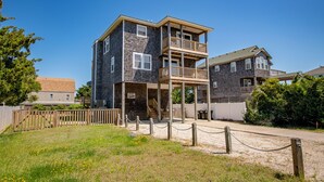 A two-story building with a balcony on the second floor, a covered entrance, and a fenced yard. - Pet Friendly, fenced in Yard and Huge Pool! Sound Views, 2 min walk to Ocean (Waves)