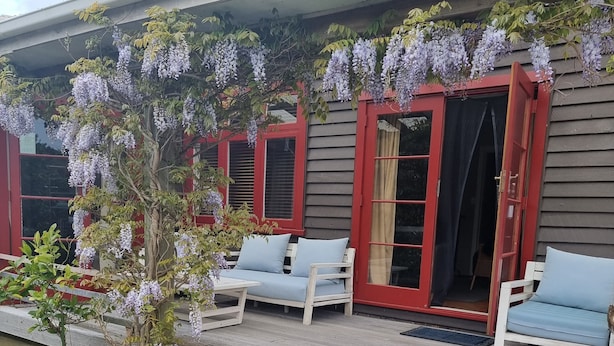 En veranda med to hvide stole, et lille bord og en plantekasse.