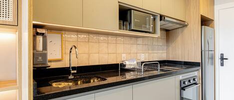 A modern kitchen with a stainless steel refrigerator, a microwave, a built-in oven, and a sink with a faucet.