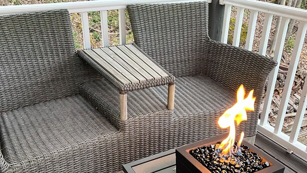 A wicker sofa and a small table on a wooden deck with a fire feature. - Tranquil creek side retreat (Canandaigua)