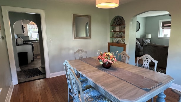 Zona pranzo con un tavolo in legno, sedie blu e un vaso di fiori.