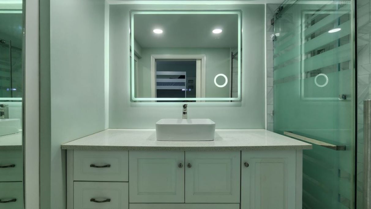 A modern bathroom with a white vanity, a large mirror, and a glass shower enclosure.