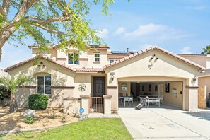 A two-story house with a garage, a covered patio, and a well-maintained lawn.