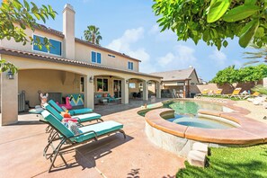 A house with a swimming pool, lounge chairs, and a patio area.