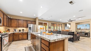 A modern kitchen with wooden cabinets, stainless steel appliances, and a large island. - Desert Oasis w/Pool, Spa & more! (Coachella)