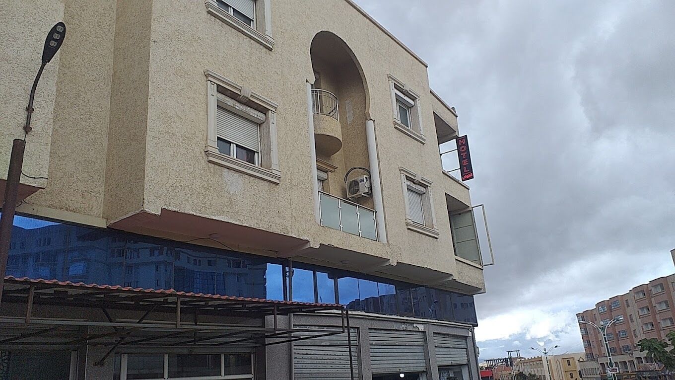A multi-story building with a beige facade, multiple windows, and a balcony.