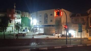 A nighttime urban street scene with buildings, traffic lights, and a wet road.
