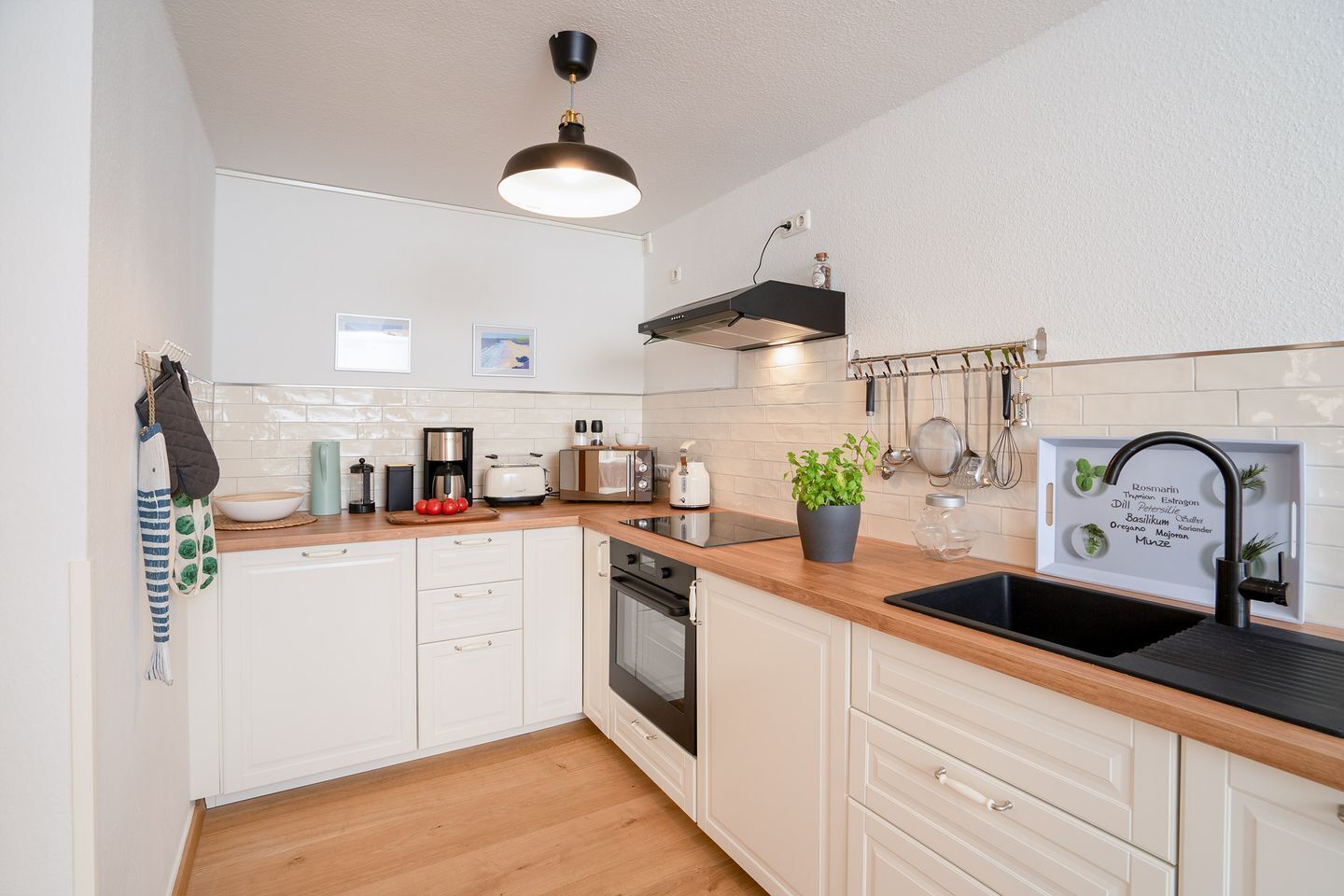 Een moderne keuken met witte kasten, een houten aanrecht, een koffiezetapparaat, een broodrooster en een spoelbak met een zwarte kraan.