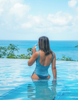 A woman in a blue swimsuit sitting in a pool with a view of the ocean. - Homey 1 K-Bed Villa with Living Rm Sofa Bed.  Ask about 2nd Rm w/Bunkbed Option (Castries)