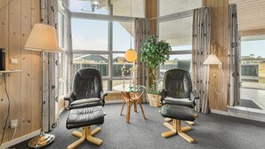A modern room with two leather chairs, a glass table, a potted plant, and large windows. - Stunning home in Henne with sauna (Henne)