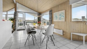 A modern dining area with a round table, white chairs, and a wooden ceiling. - Stunning home in Henne with sauna (Henne)