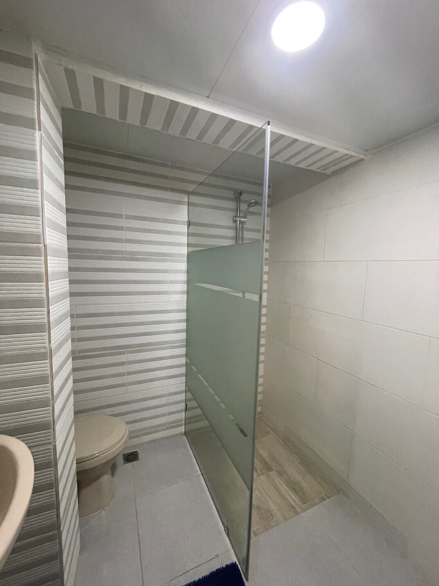 A bathroom with a toilet, a glass shower enclosure, and a sink.