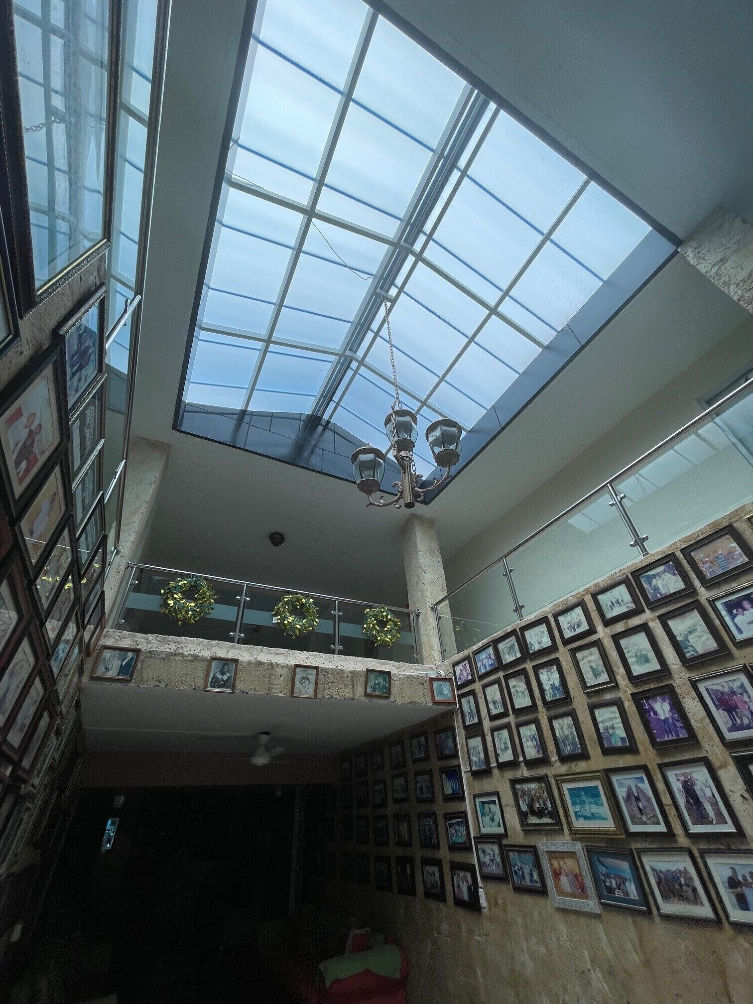Een meerlaags interieur met dakraam, ingelijste foto's aan de muur en een kroonluchter.