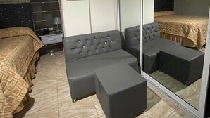 Une chambre à coucher comprenant un lit, un canapé, une table de chevet, un miroir et une armoire.