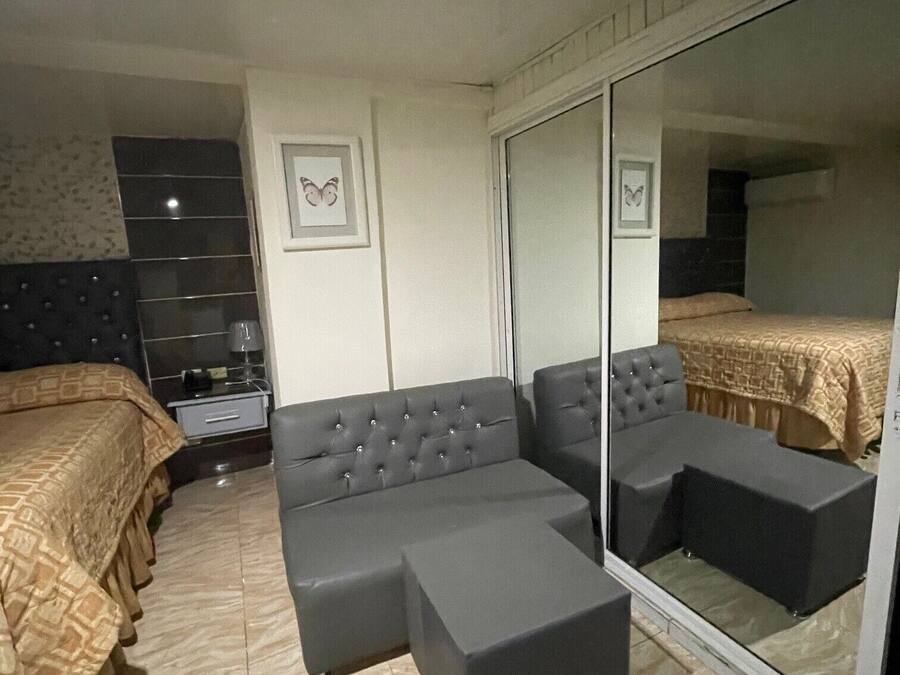 A bedroom with a bed, a sofa, a nightstand, a mirror, and a wardrobe.