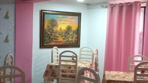 Un coin repas avec des murs roses, un tableau et des nappes à motifs floraux.
