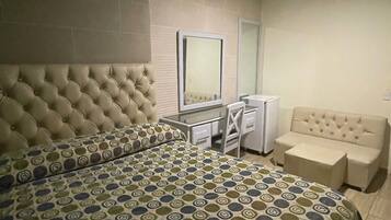 Ein Hotelzimmer mit einem großen Bett, einem Schreibtisch, einem Sessel und einer Couch.