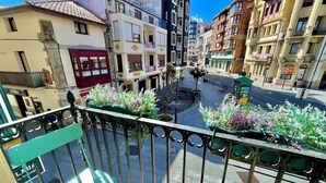 Een balkon met metalen hekwerk en bloempotten.